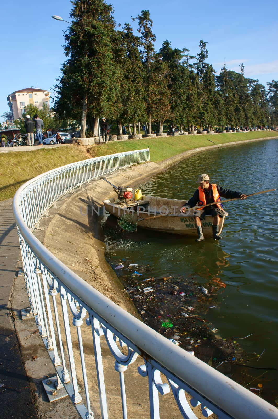 DA LAT, VIET NAM- DEC 29: Vietnamese sanitation worker working on Xuan Huong lake, he's  sit on boat and pick up trash from surface water to clean up the lake in Dalat, Vietnam on Dec 29, 2013