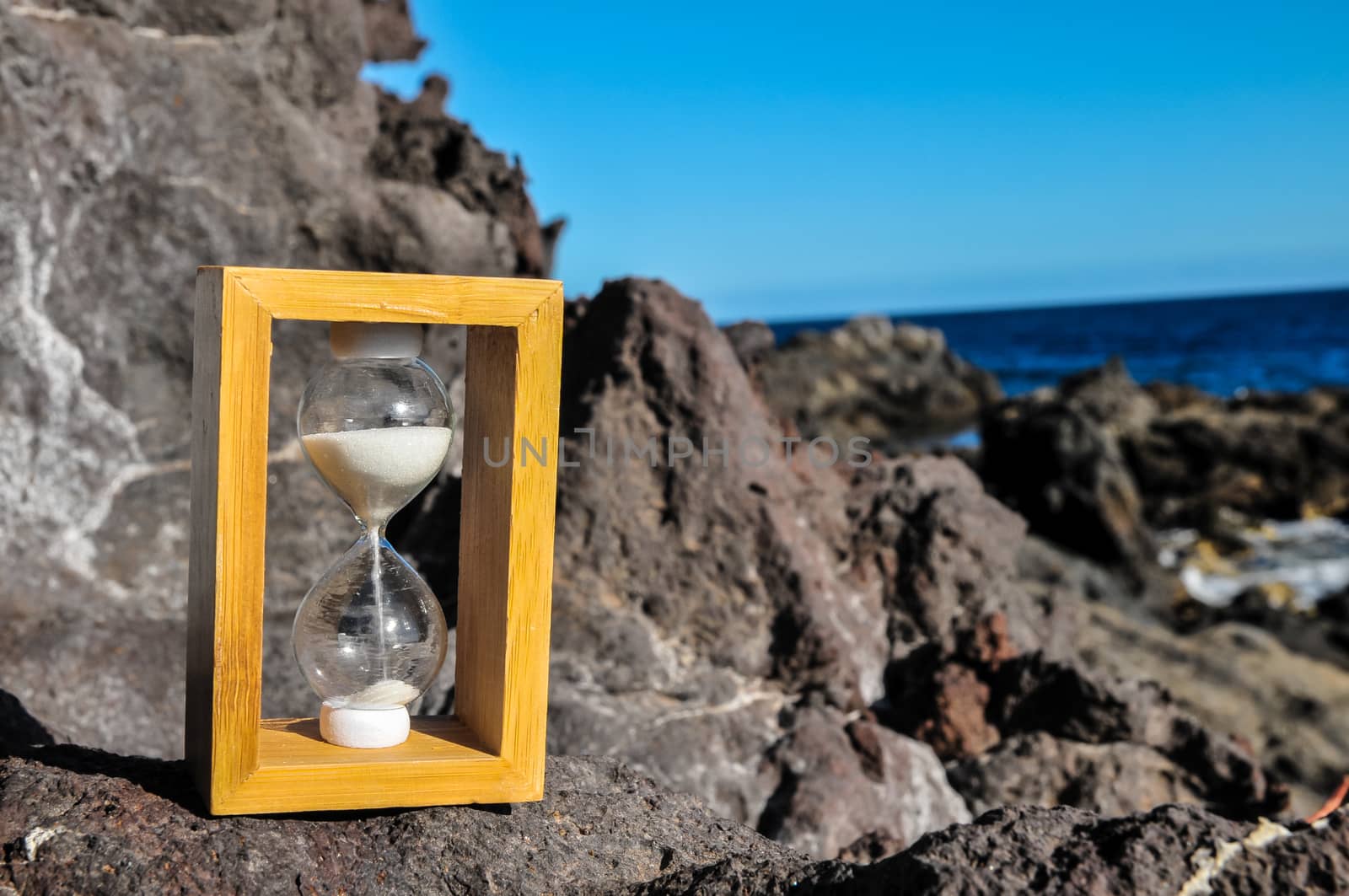 Time Concept White Sand Hourglass on the Volcanic Rocks