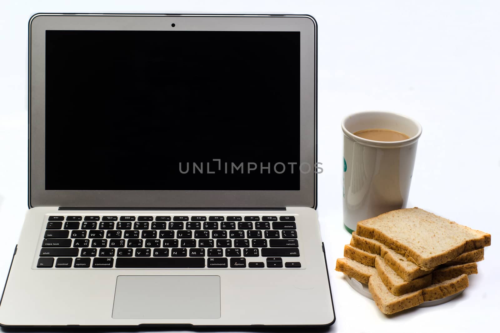 Office desk with laptop, bread and cup of coffee