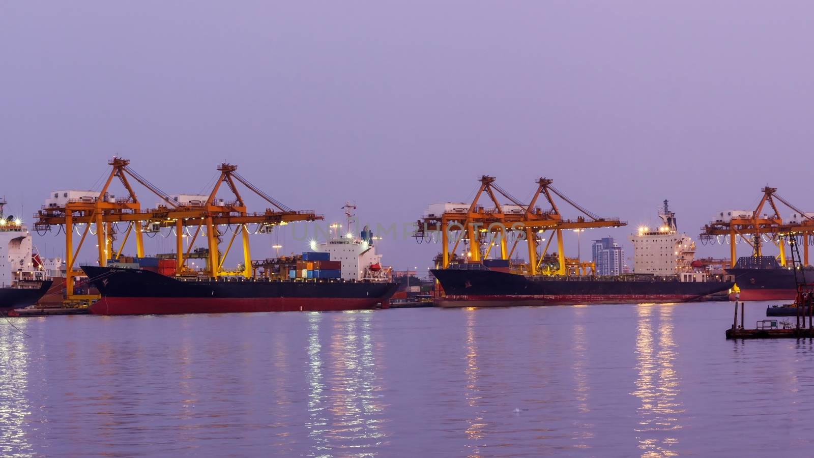 Big crane bridge shipping container cargo in shipyard at twiligh by ngungfoto