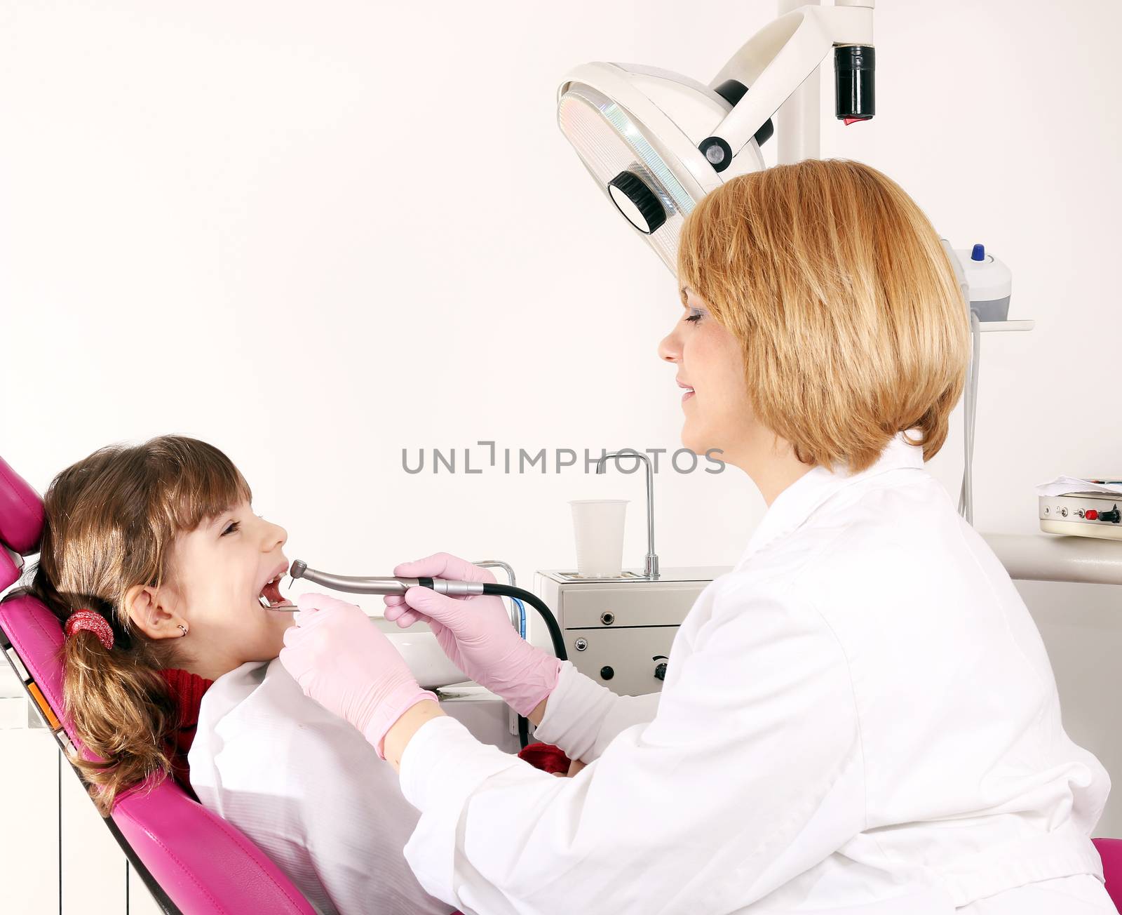 little girl and dentist drilling treatment