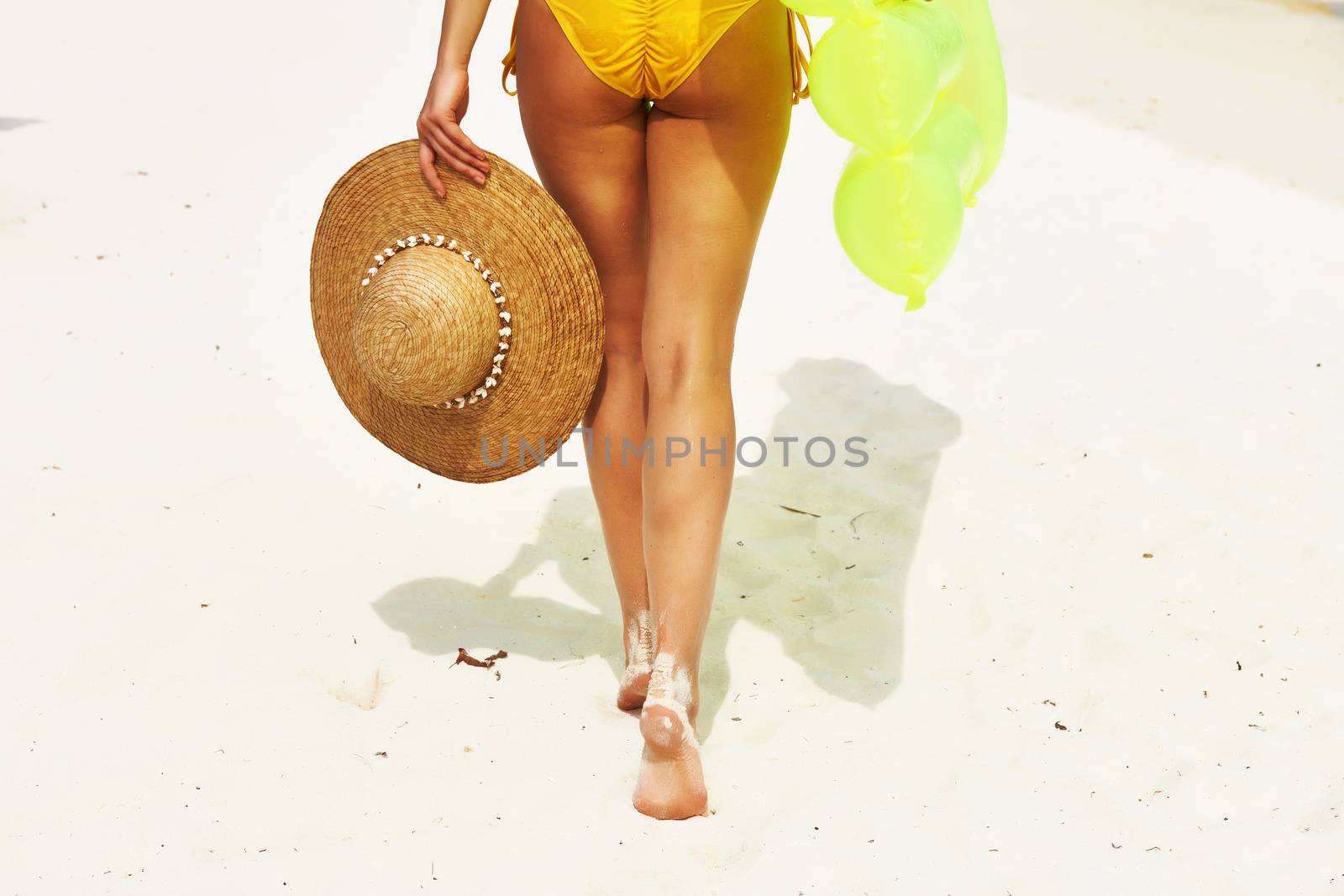 Woman with yellow inflatable raft walking at the beach