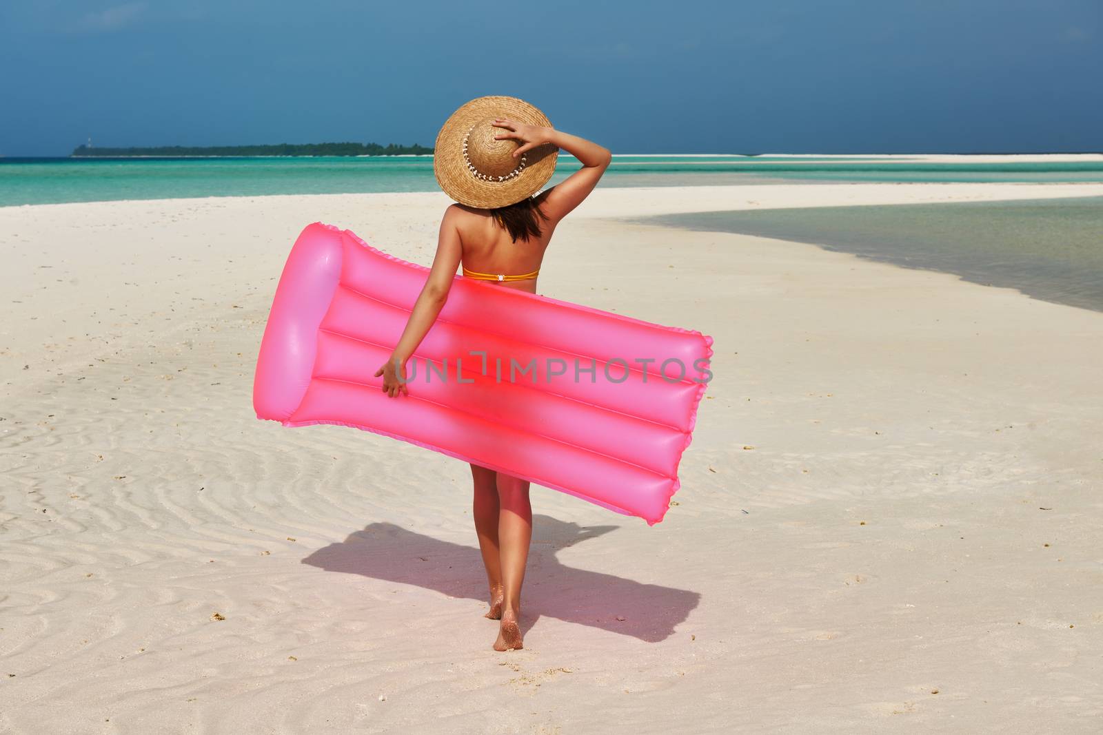 Woman with pink inflatable raft walking at the beach