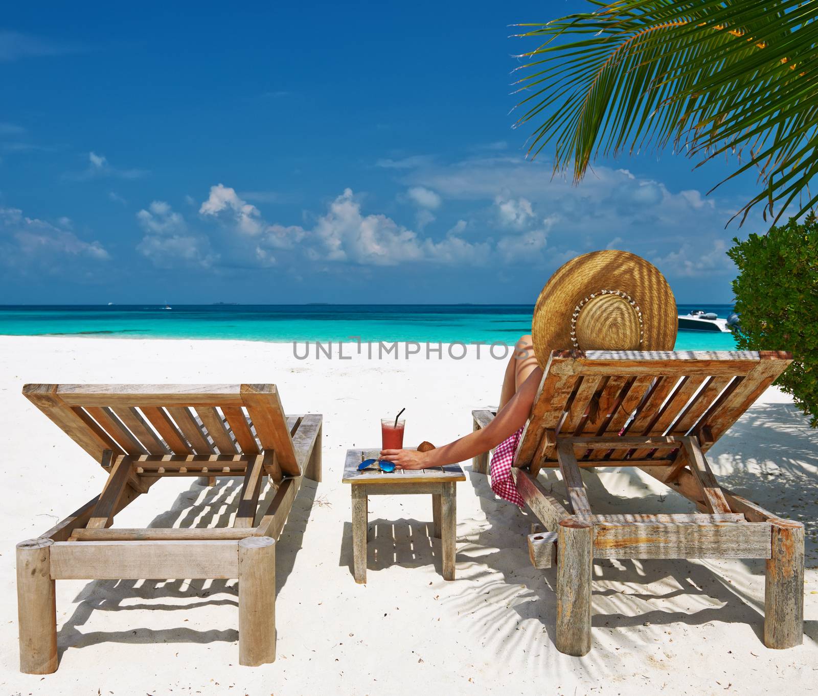 Woman at beach with chaise-lounges by haveseen