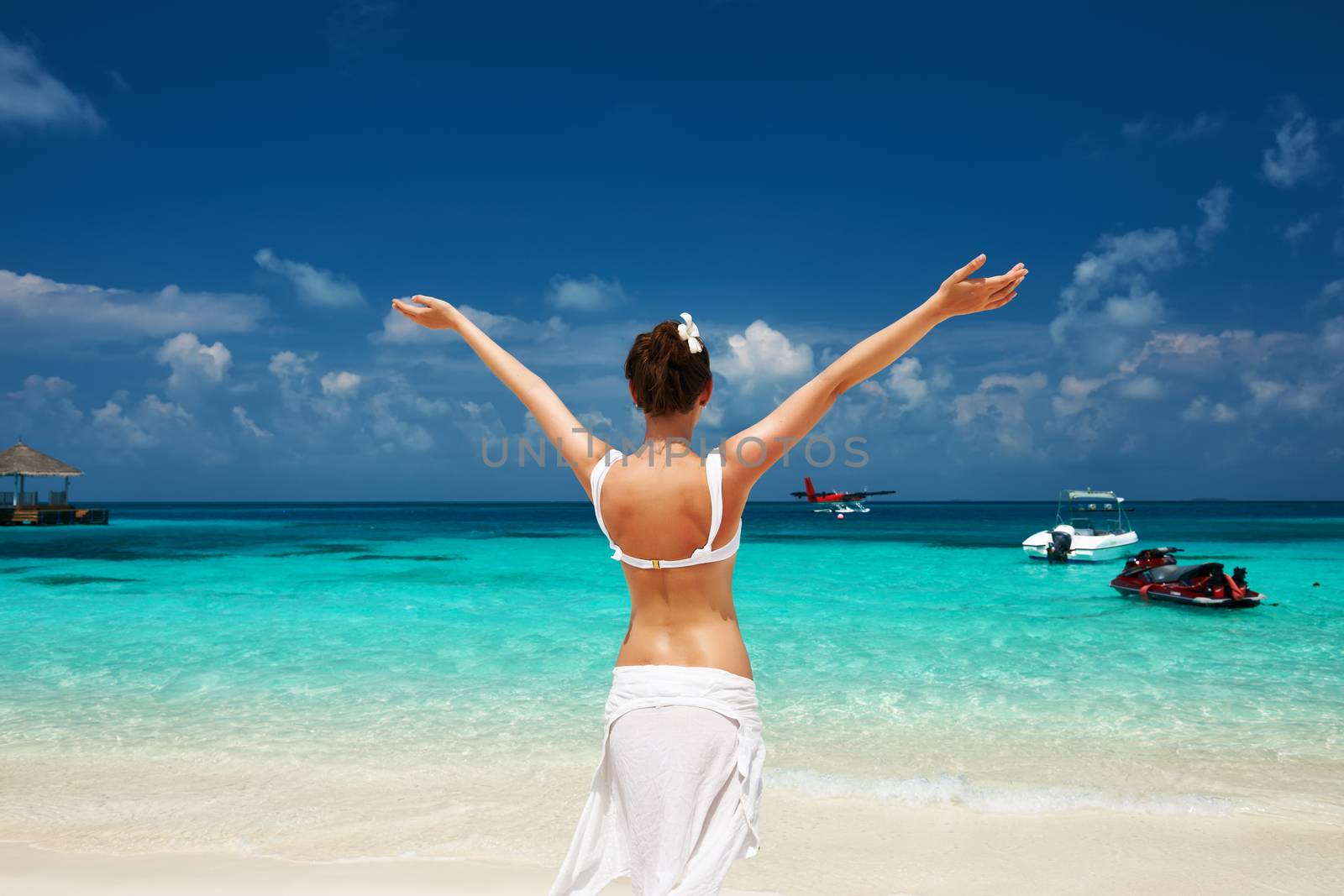Woman in bikini at tropical beach. Seaplane at background.