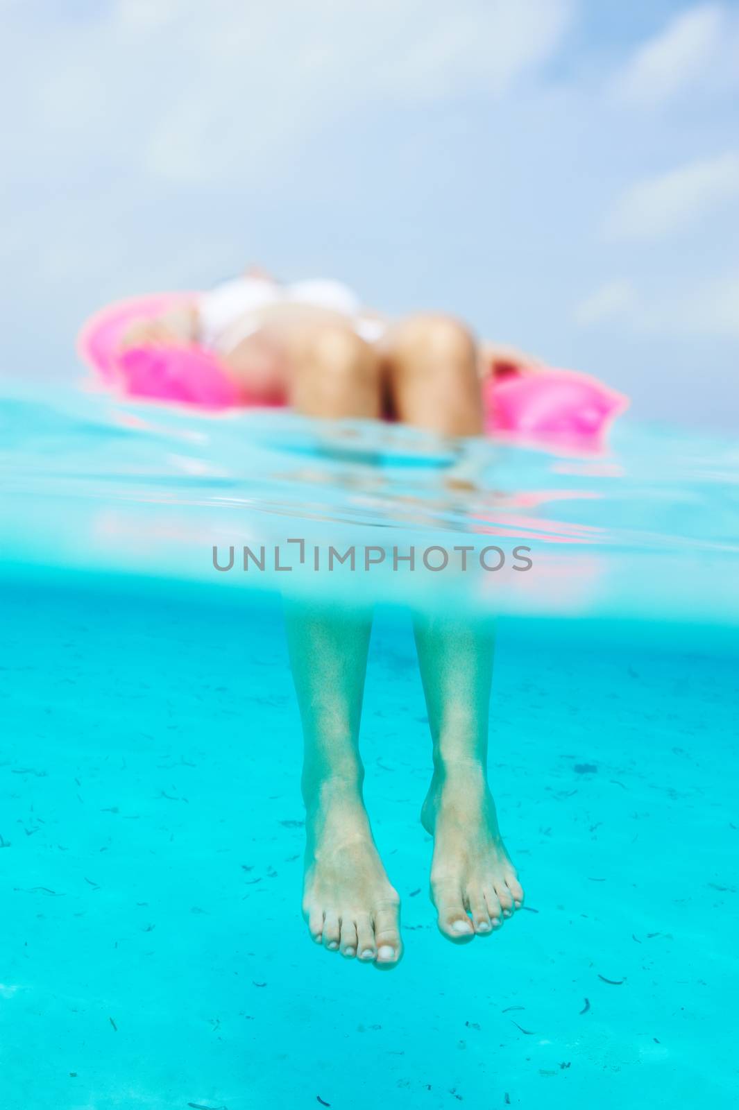 Woman relaxing on inflatable mattress, view from underwater by haveseen