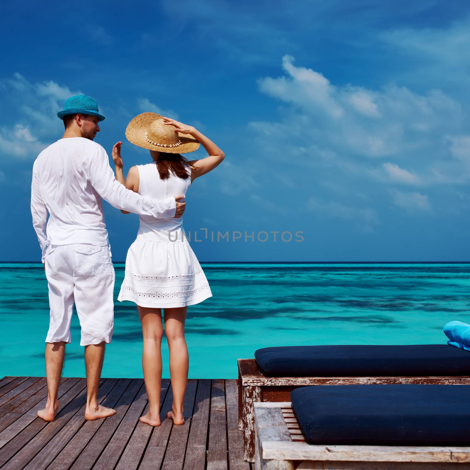 Couple on a tropical beach jetty at Maldives