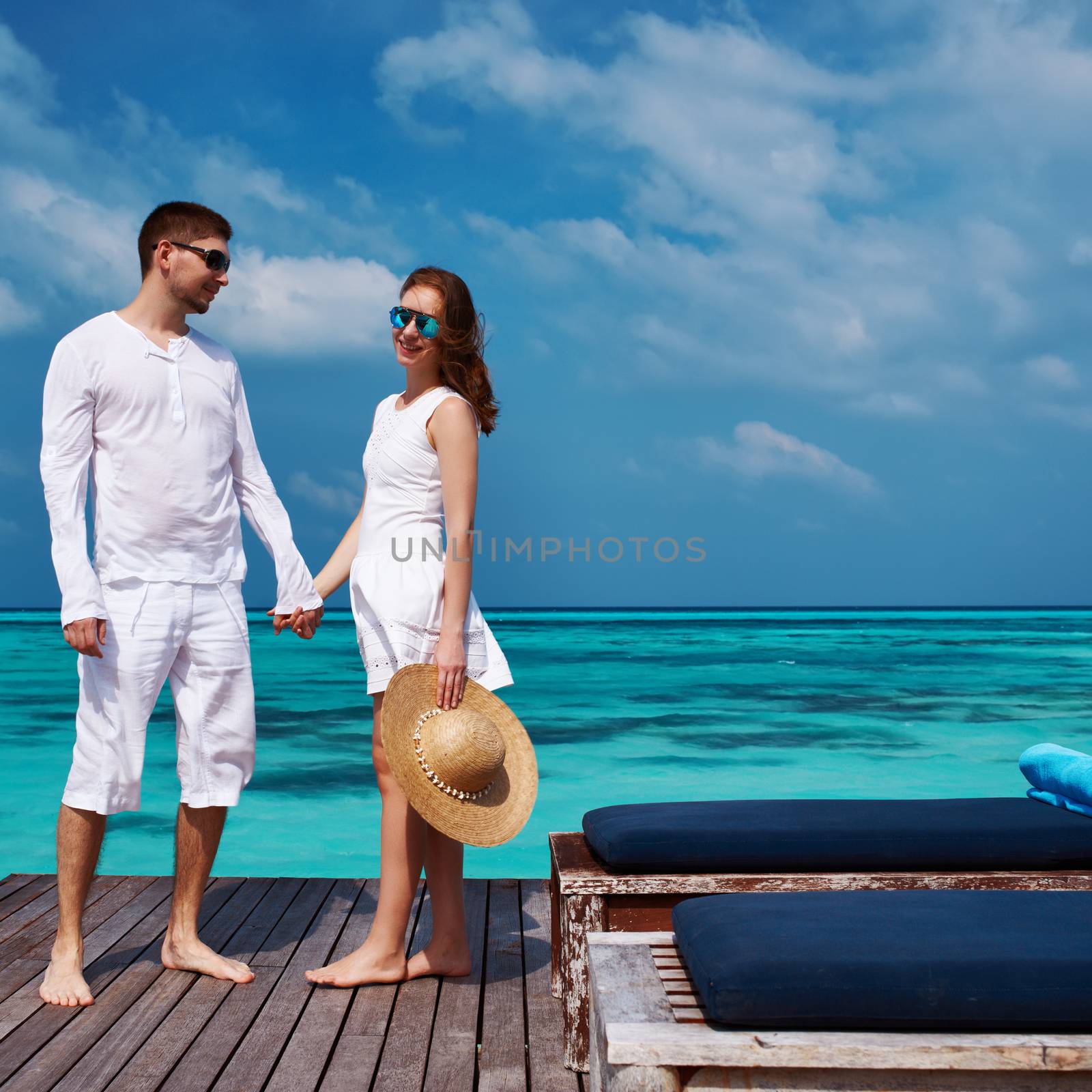 Couple on a tropical beach jetty at Maldives