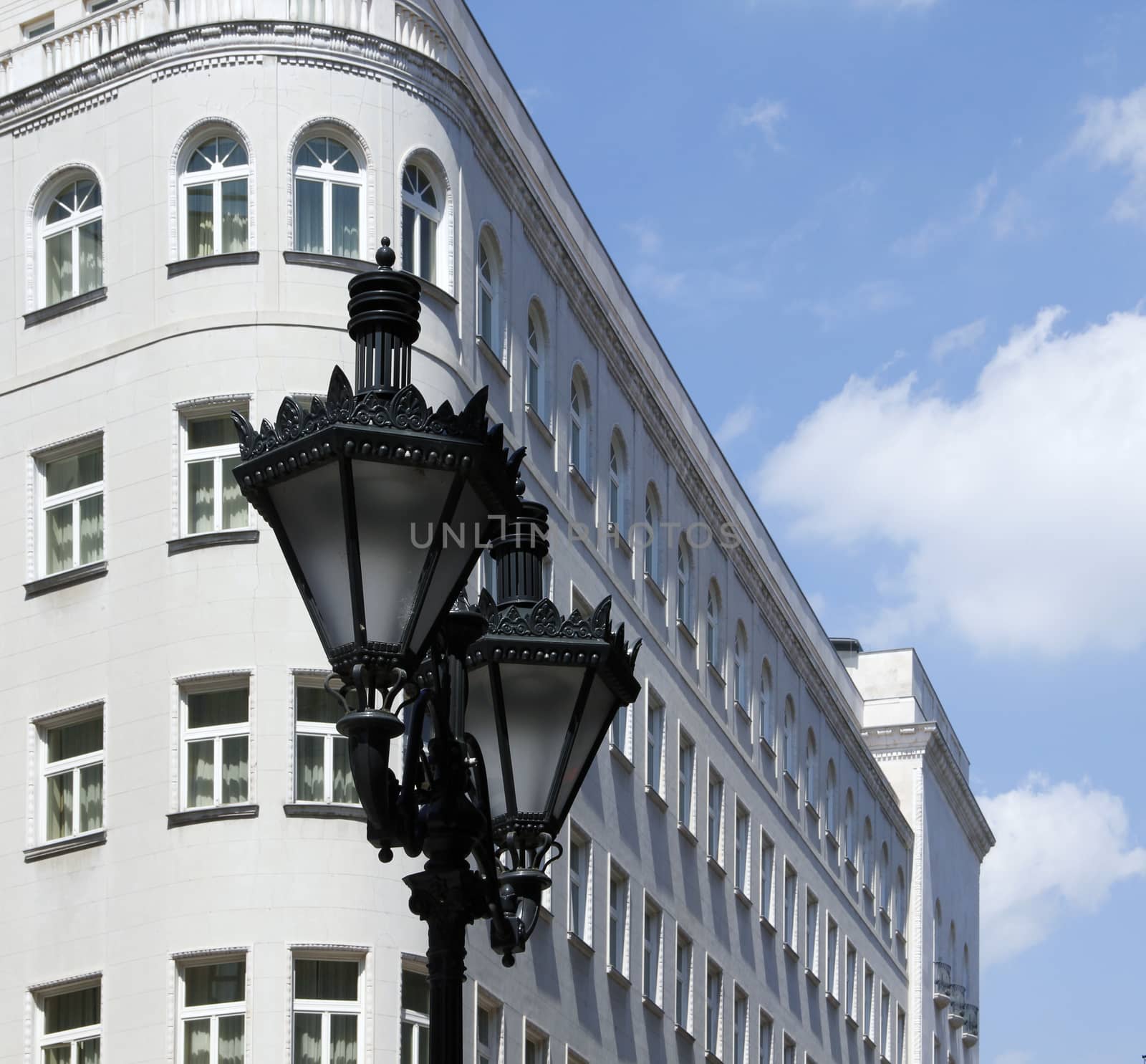 Ornate metal street lamp white building in the background.