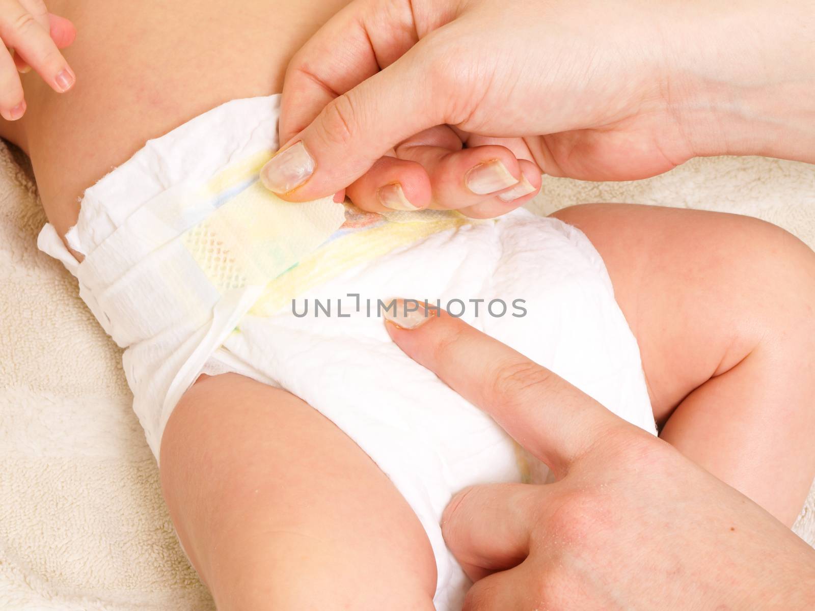 Diaper change on a newborn baby by female with manicure