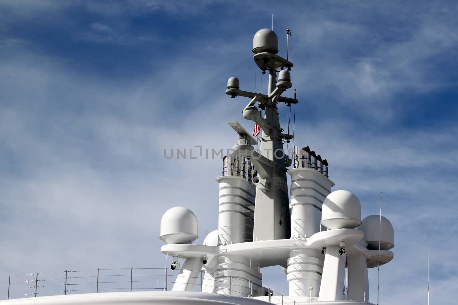 Radar system on to of a ship with blue cloudy sky in the background.