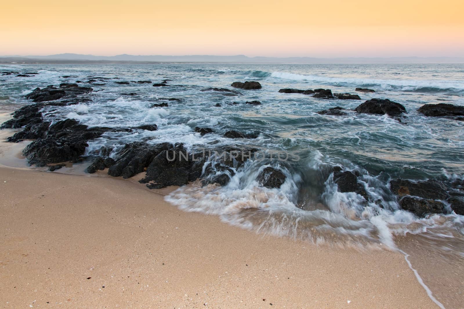 Rough sea and golden sand at the rugged coast in South Africa