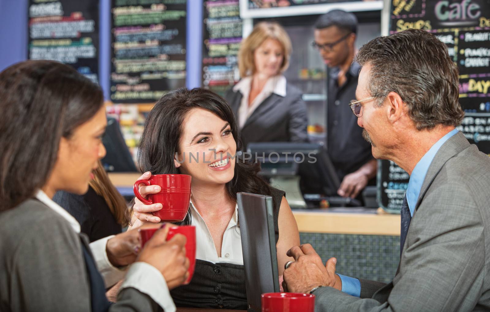 Three adult business people meeting at indoor cafe