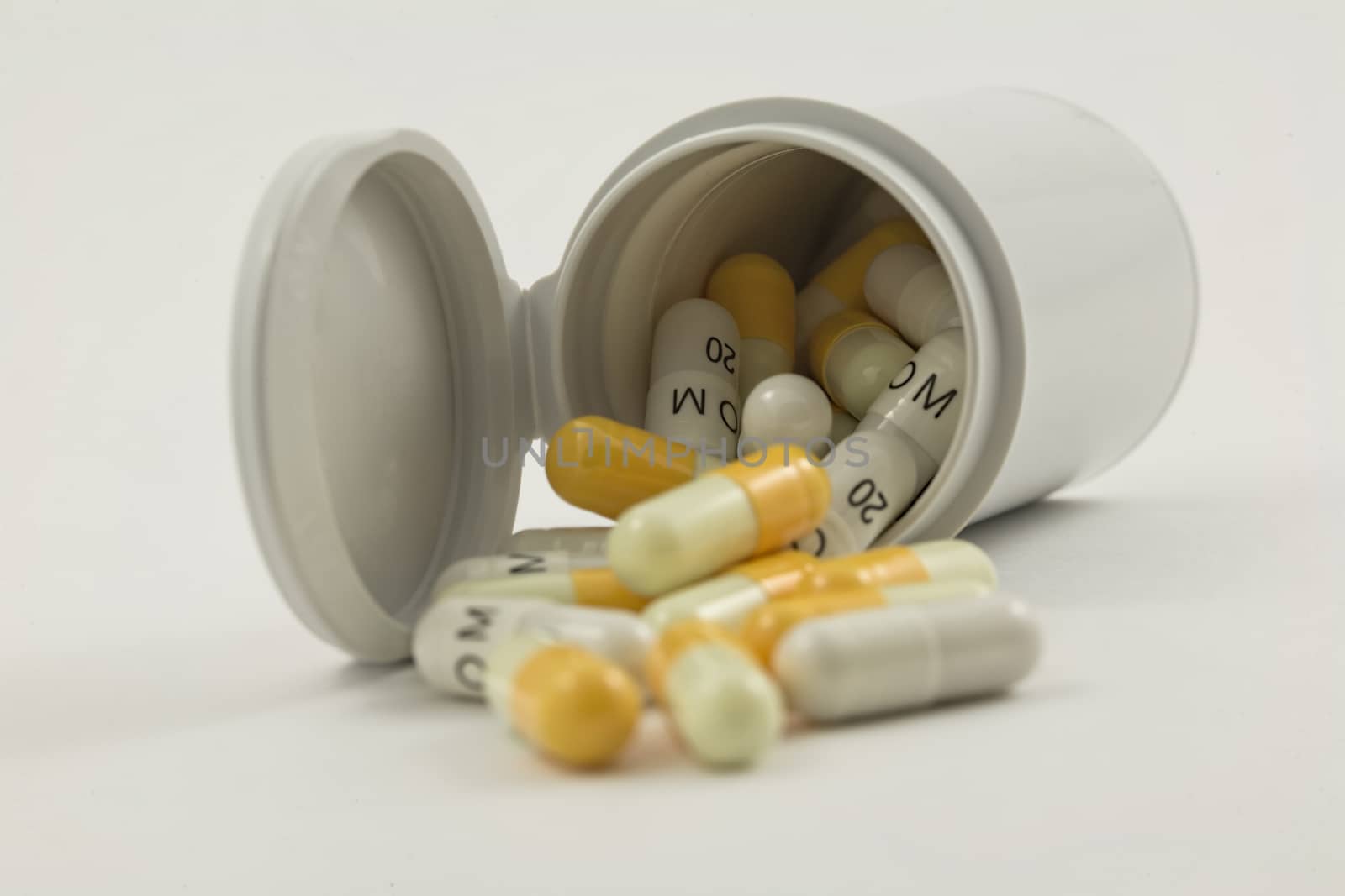 bottle with white and yellow pills isolated on a white background