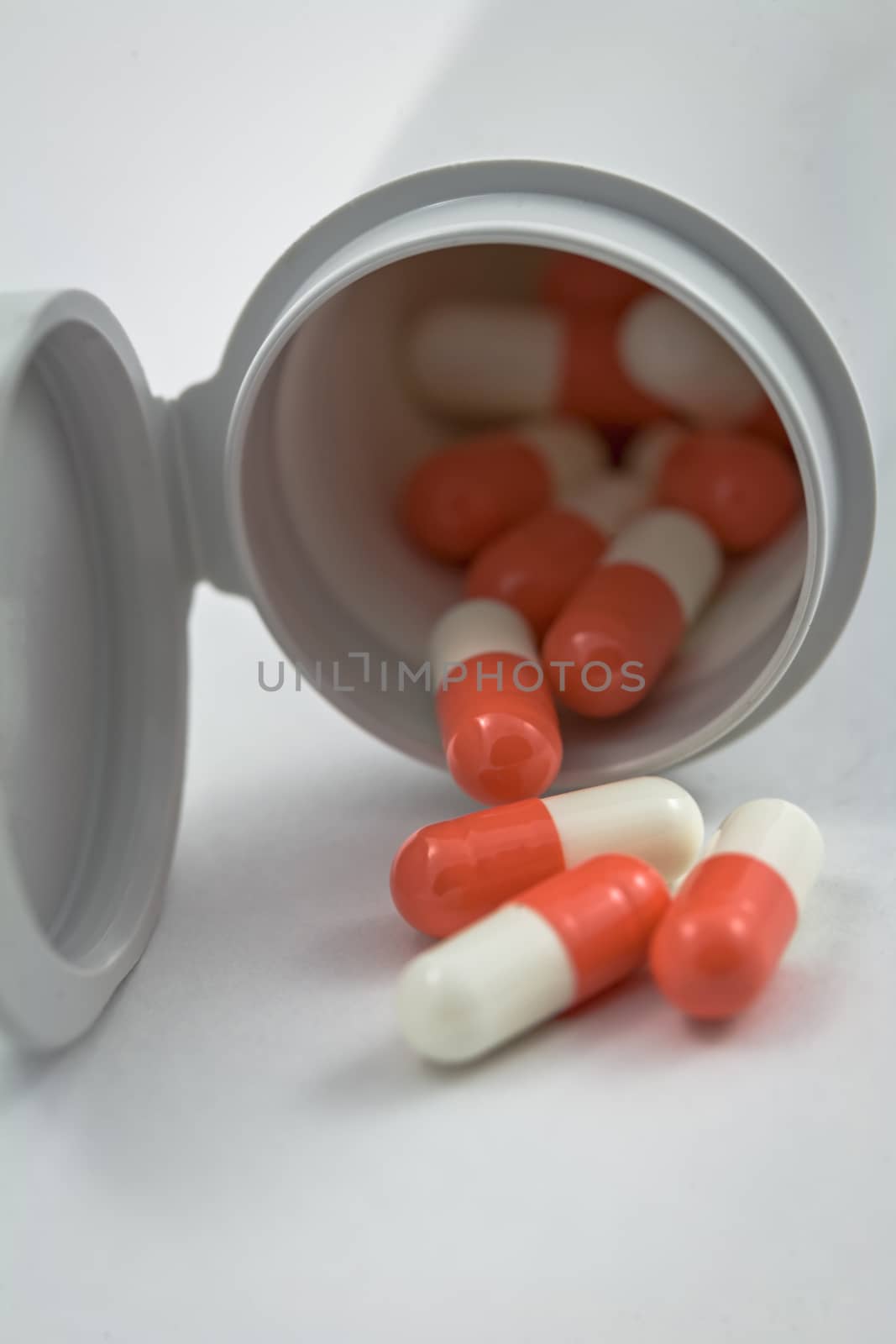 bottle with white and orange pills isolated on a white background