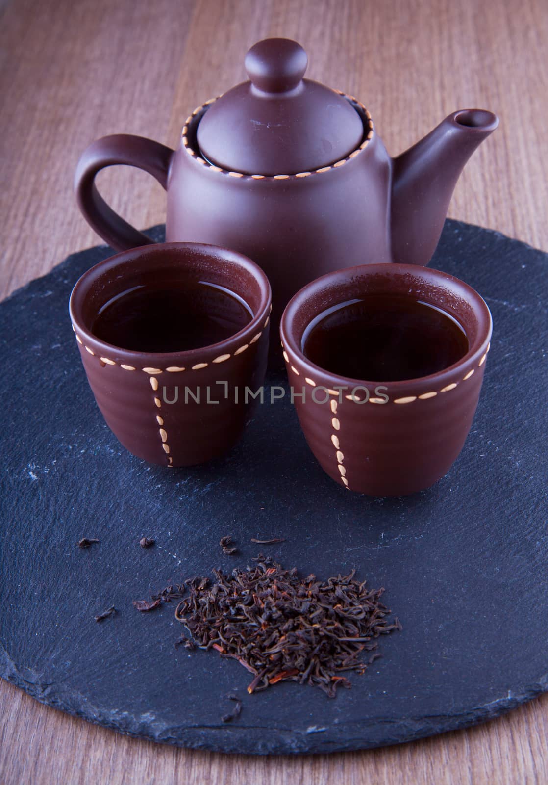 Teapot and two cops of tea with tea on the front (focus on cups)