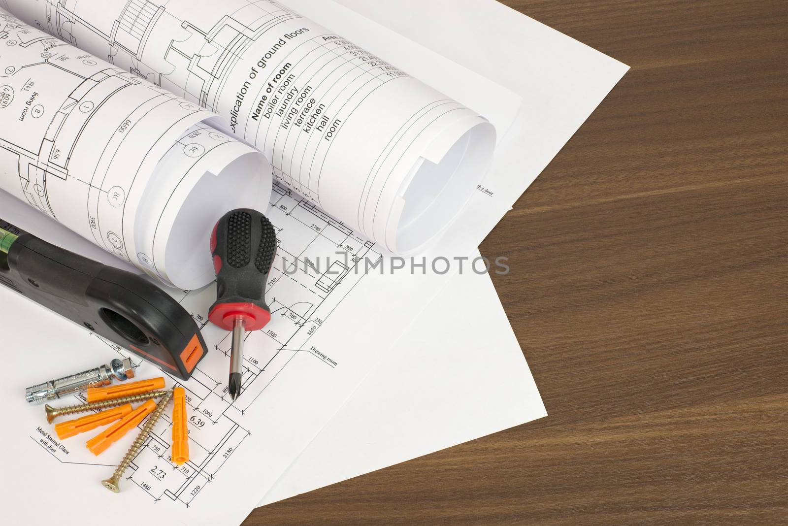 Construction drawings, screwdriver, screws and level on a wooden surface. Desk builder
