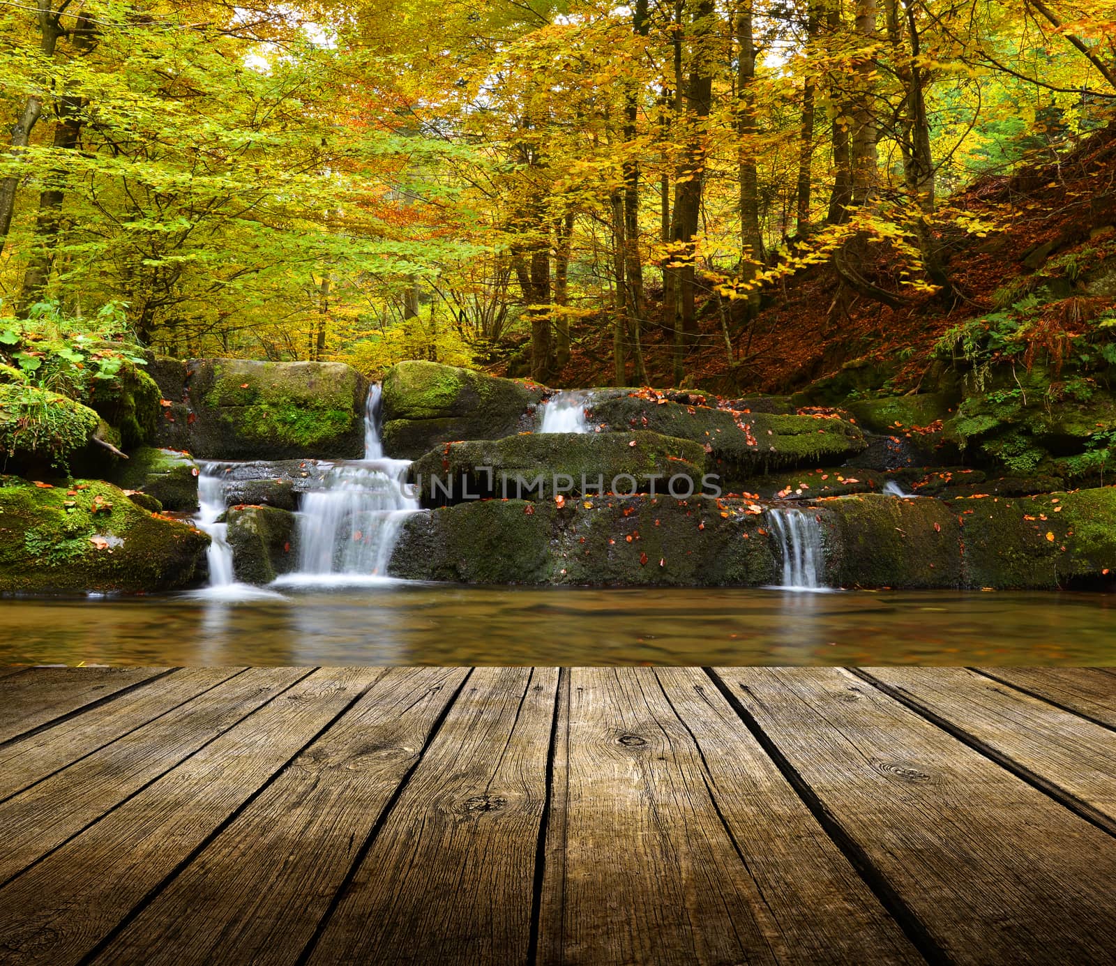 Empty wooden deck table with autumn waterfall background. Ready for product display montage. 