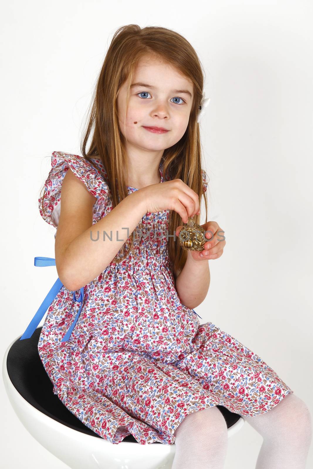Young smiling girl sitting on a chair. smelling perfume