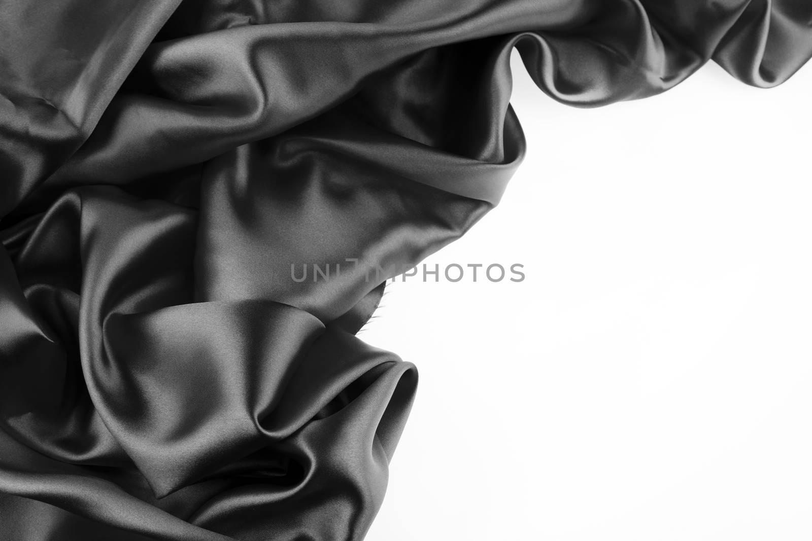 Closeup of rippled black silk fabric on plain background