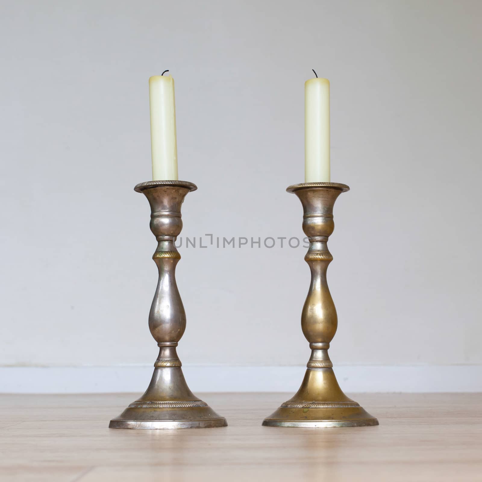 Burning candle on wooden table, white background