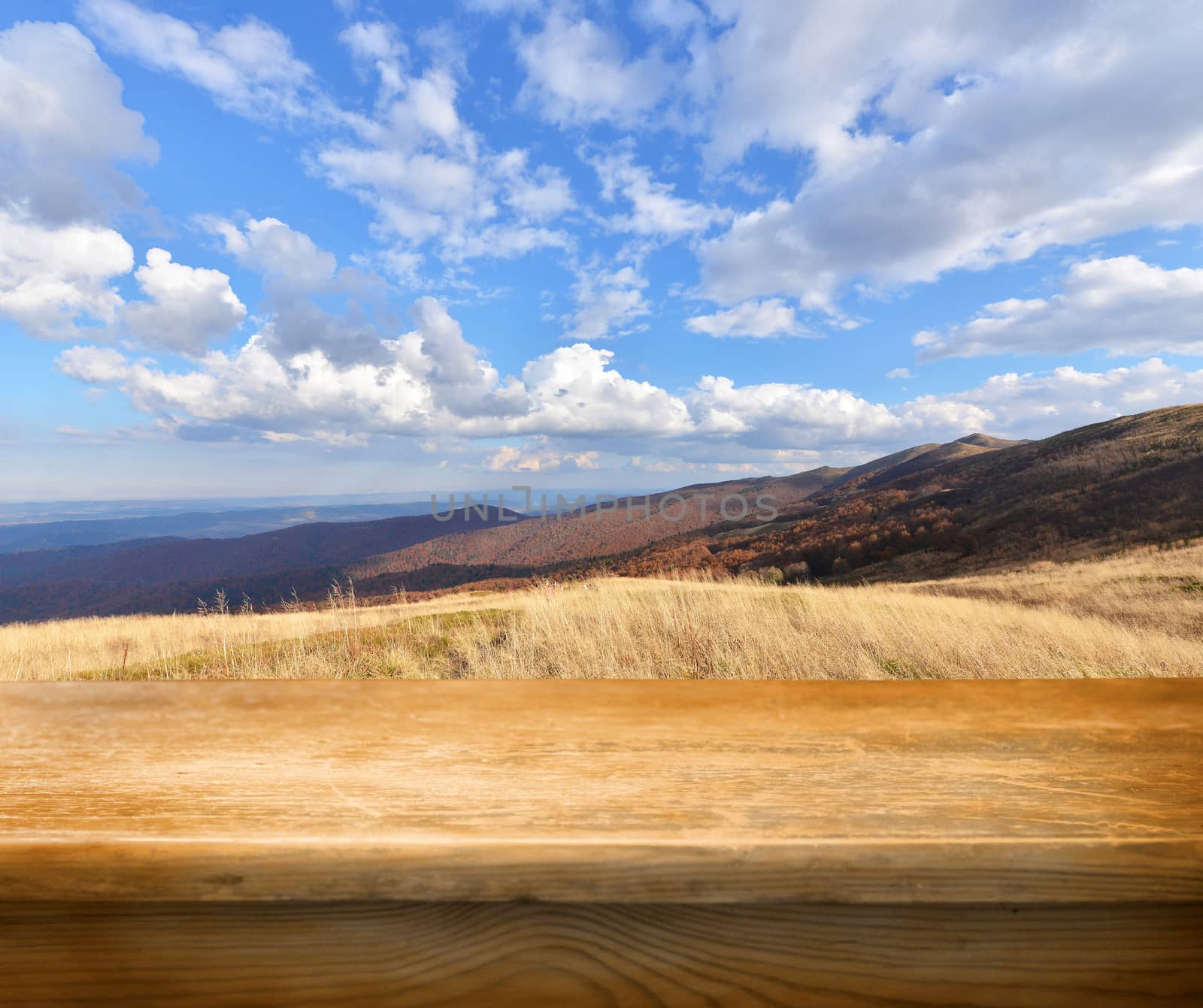 Empty wooden deck table with autumn mountains in background. Ready for product display montage.
