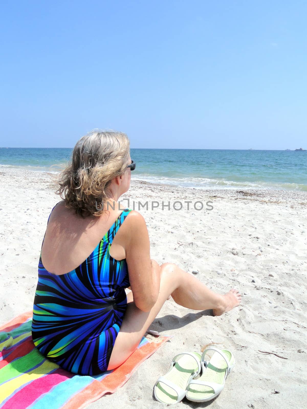 Mature female blond beauty relaxing on the beach.