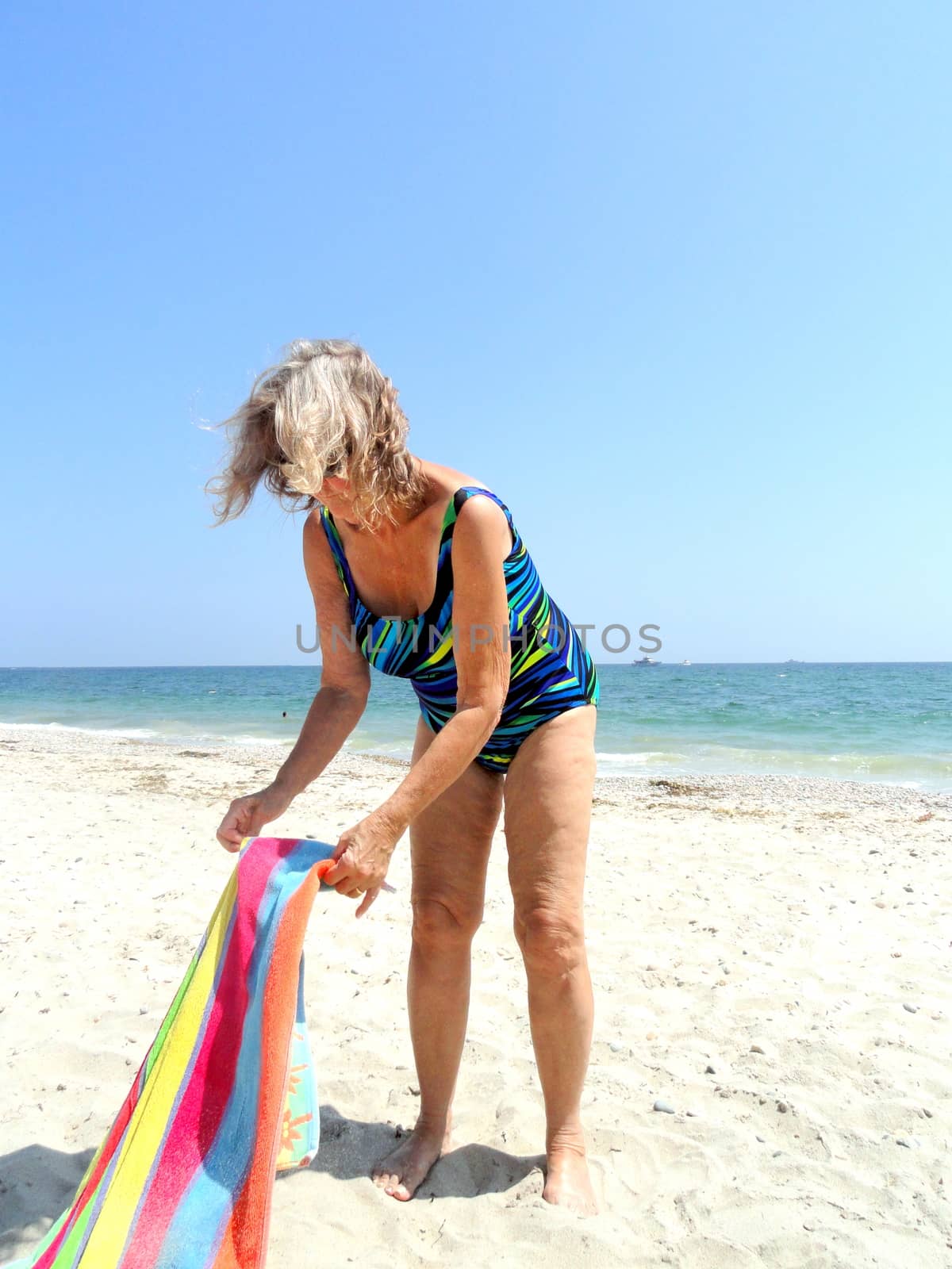 Mature female blond beauty relaxing on the beach.