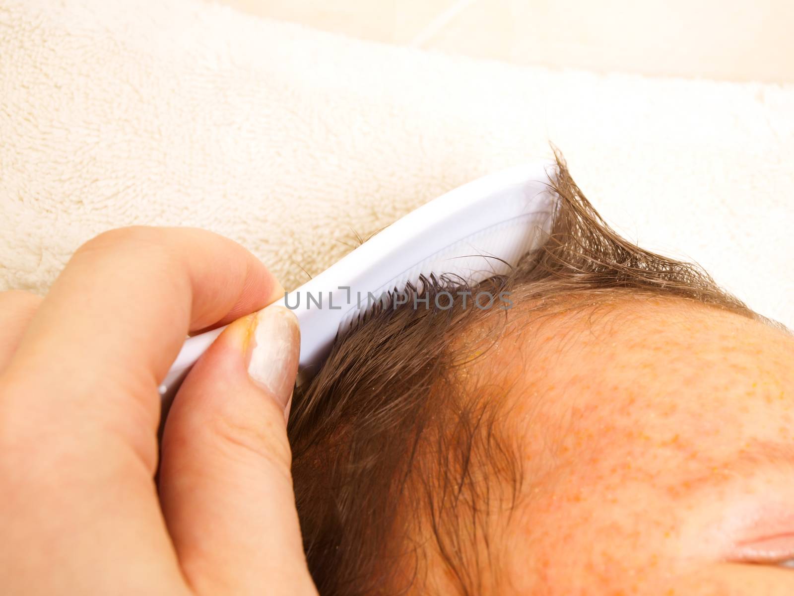 Female with manicure on thumbnail combing hair of a baby