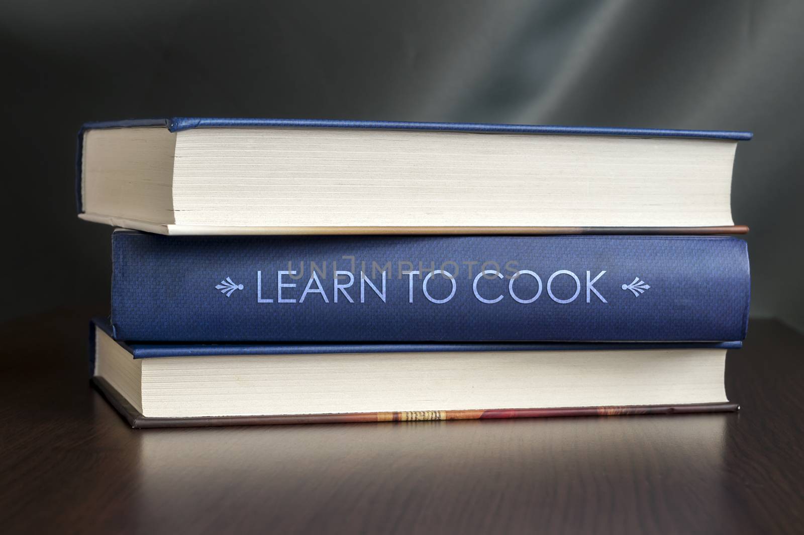 Books on a table and one with "Learn to cook" cover. Book concept.