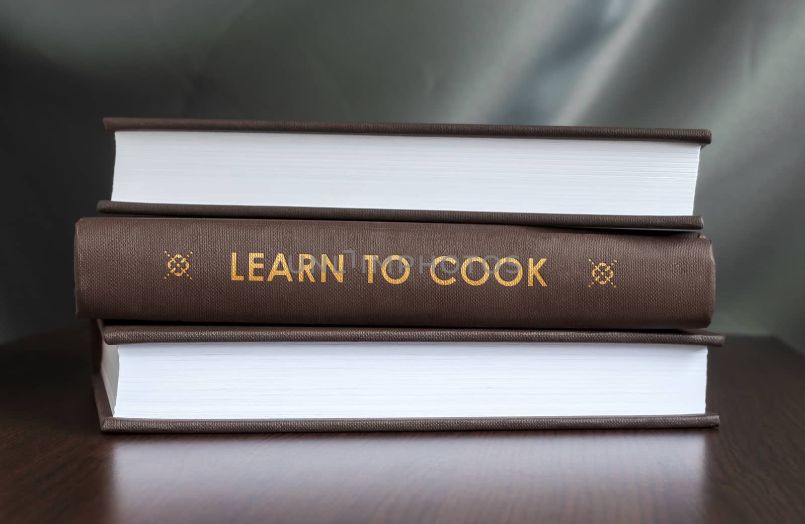 Books on a table and one with " Learn to cook. " cover. Book concept.