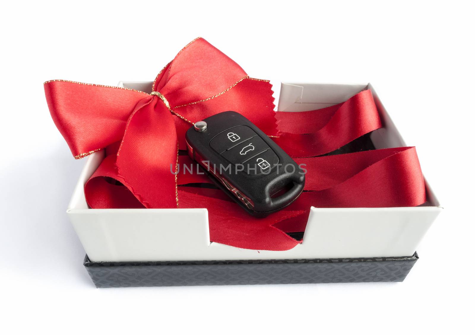 Black car key in a present box with a red ribbon
