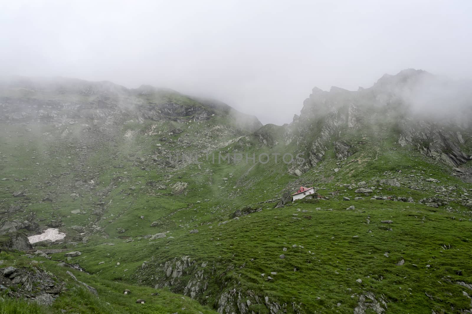 Morning mountain landscape with fog and a small building