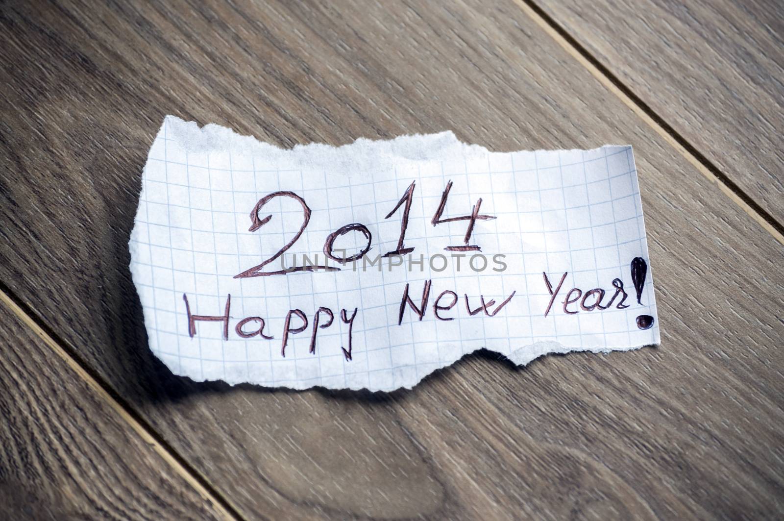 Happy new Year 2014 - Hand writing text on a piece of paper on wood background