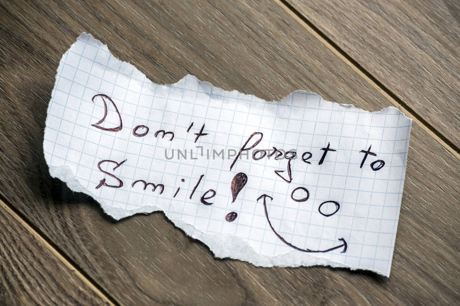 Don't forget to Smile - Hand writing text on a piece of paper on wood background