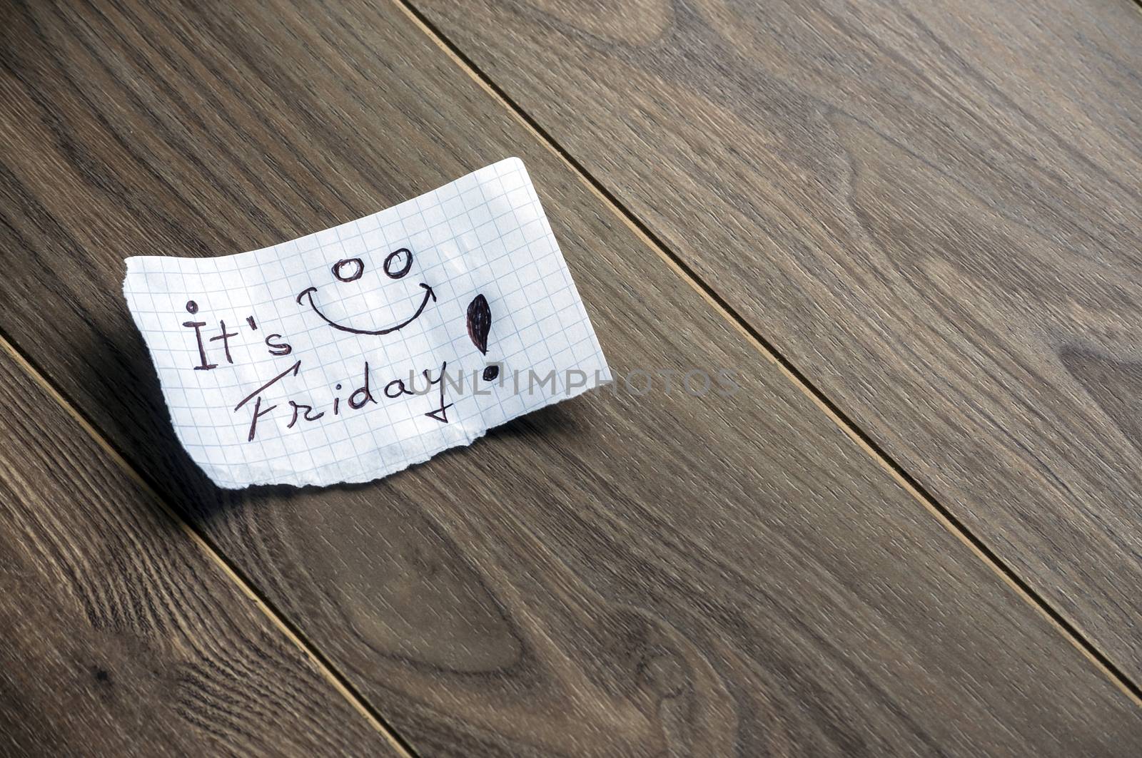 It's Friday - Hand writing text on a piece of paper on wood background with space for text