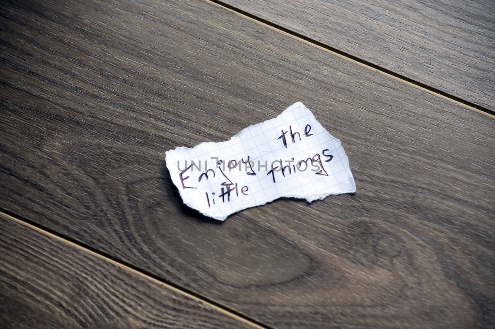 Enjoy the little things written on piece of paper, on a wood background.