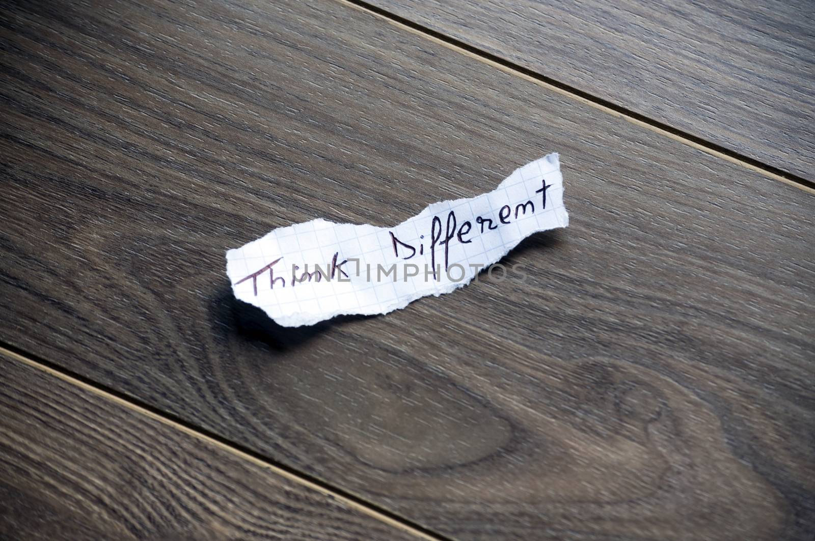 Think different written on piece of paper, on a wood background.