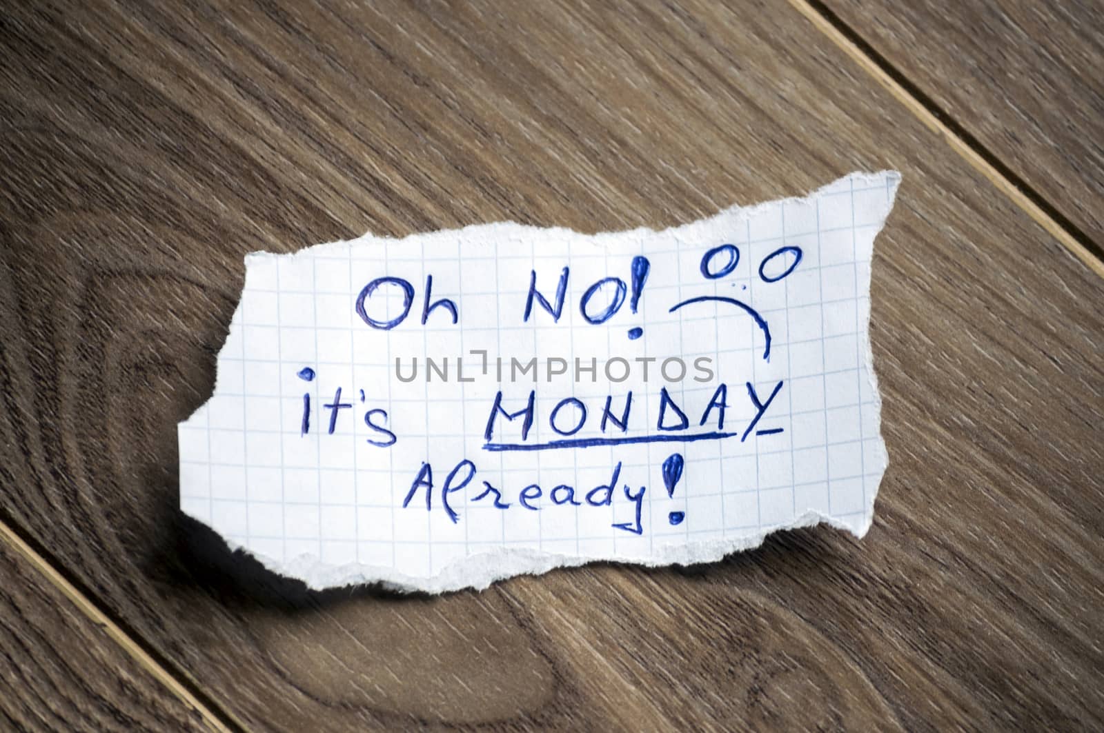 Monday message written on piece of paper, on a wood background.