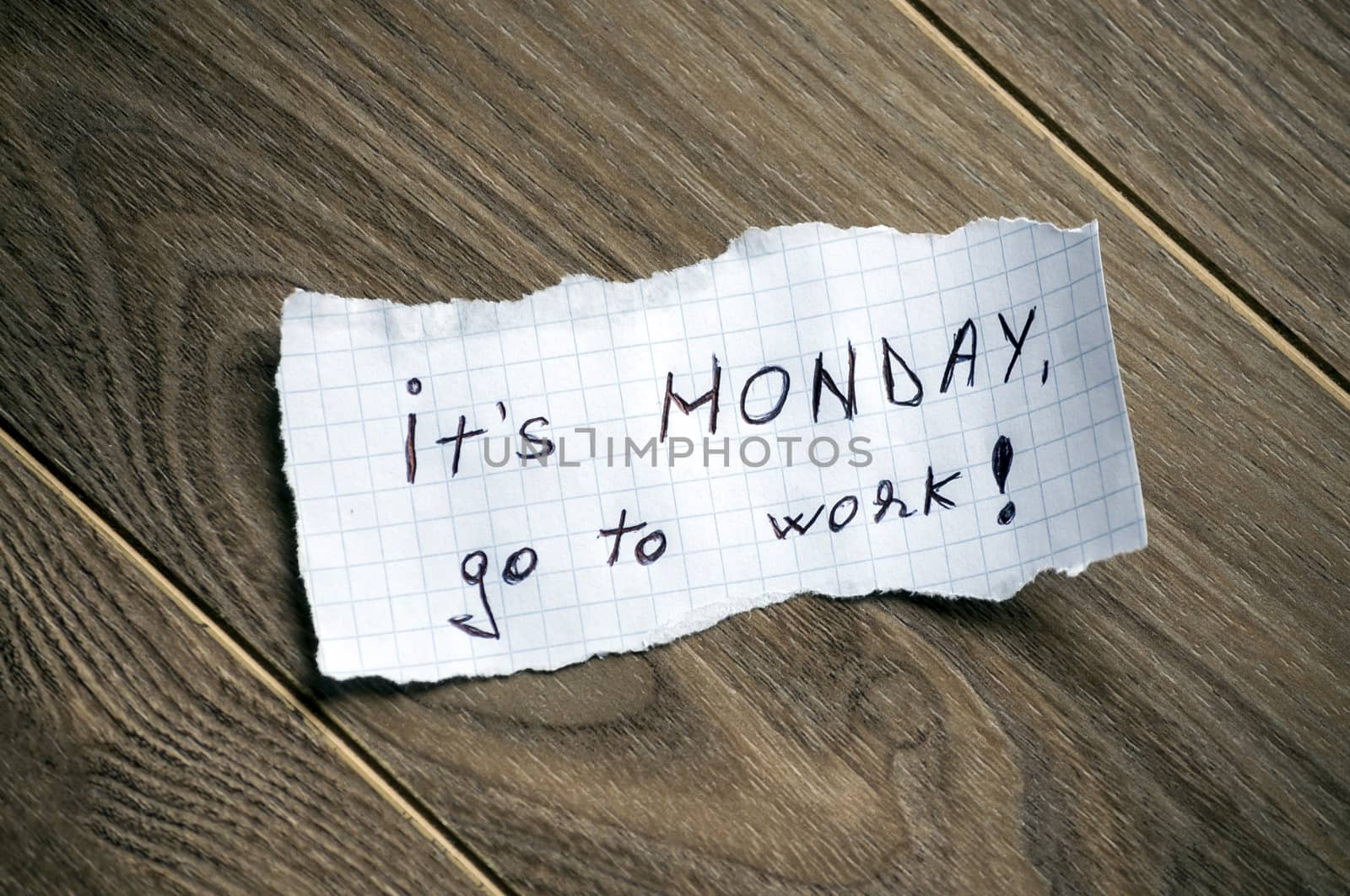 Monday message written on piece of paper, on a wood background.