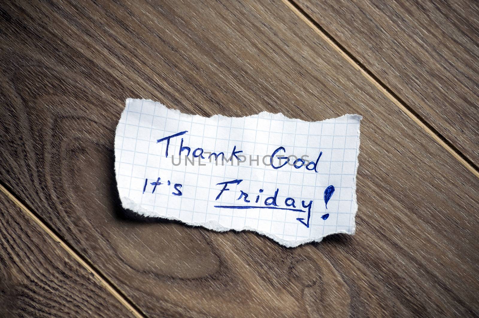 Friday message written on piece of paper, on a wood background.