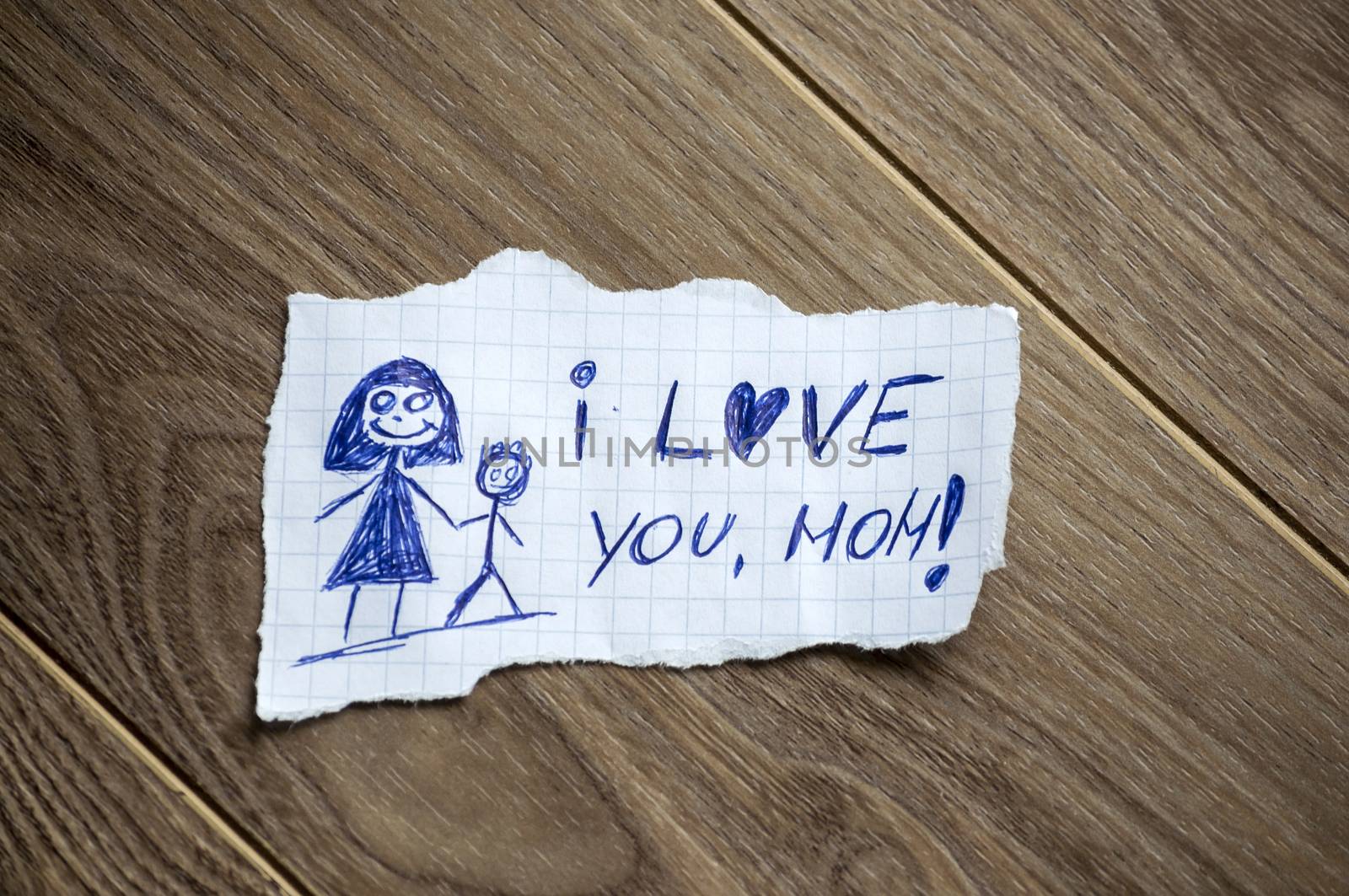 I love you, mom written on piece of paper, on a wood background