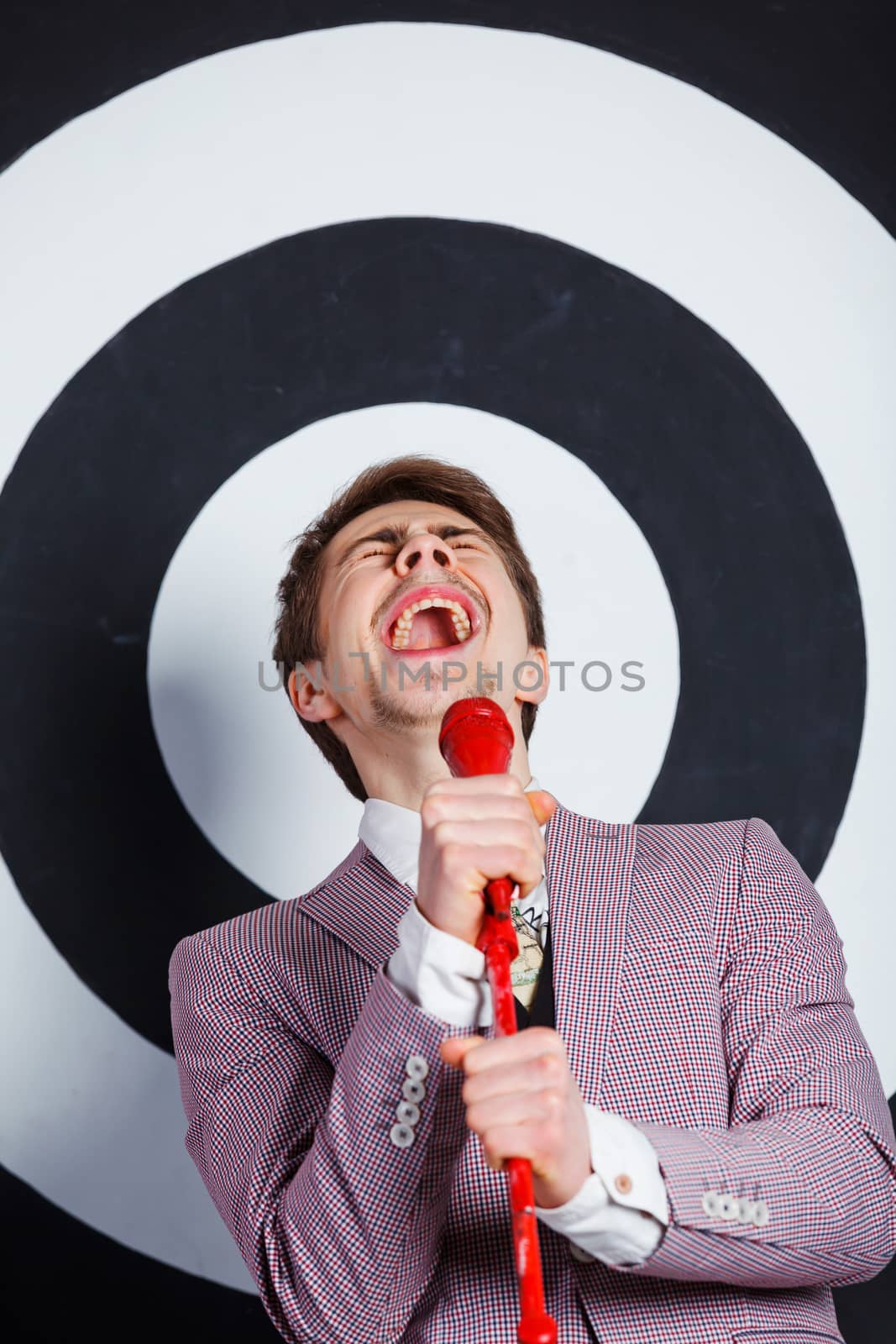 Portrait of boy in elegant jacket singing with microphone in studio