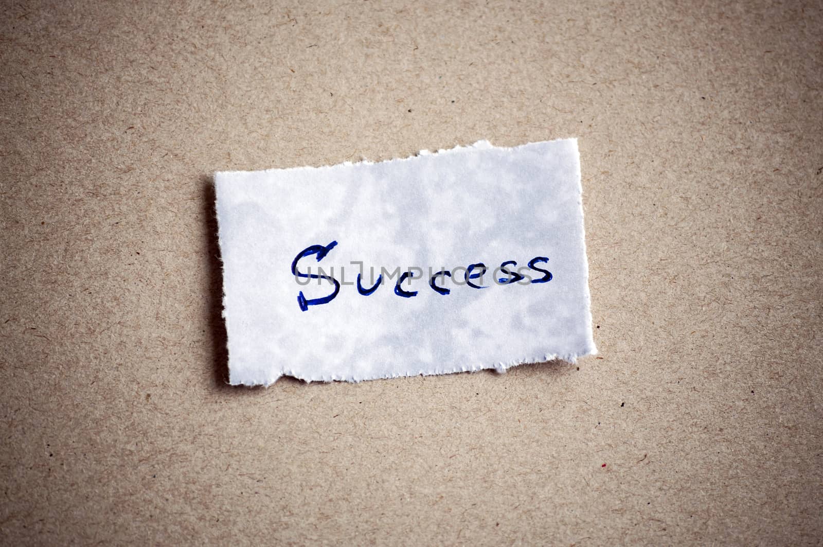 Success message,written on piece of paper, on cardboard background. Space for your text.