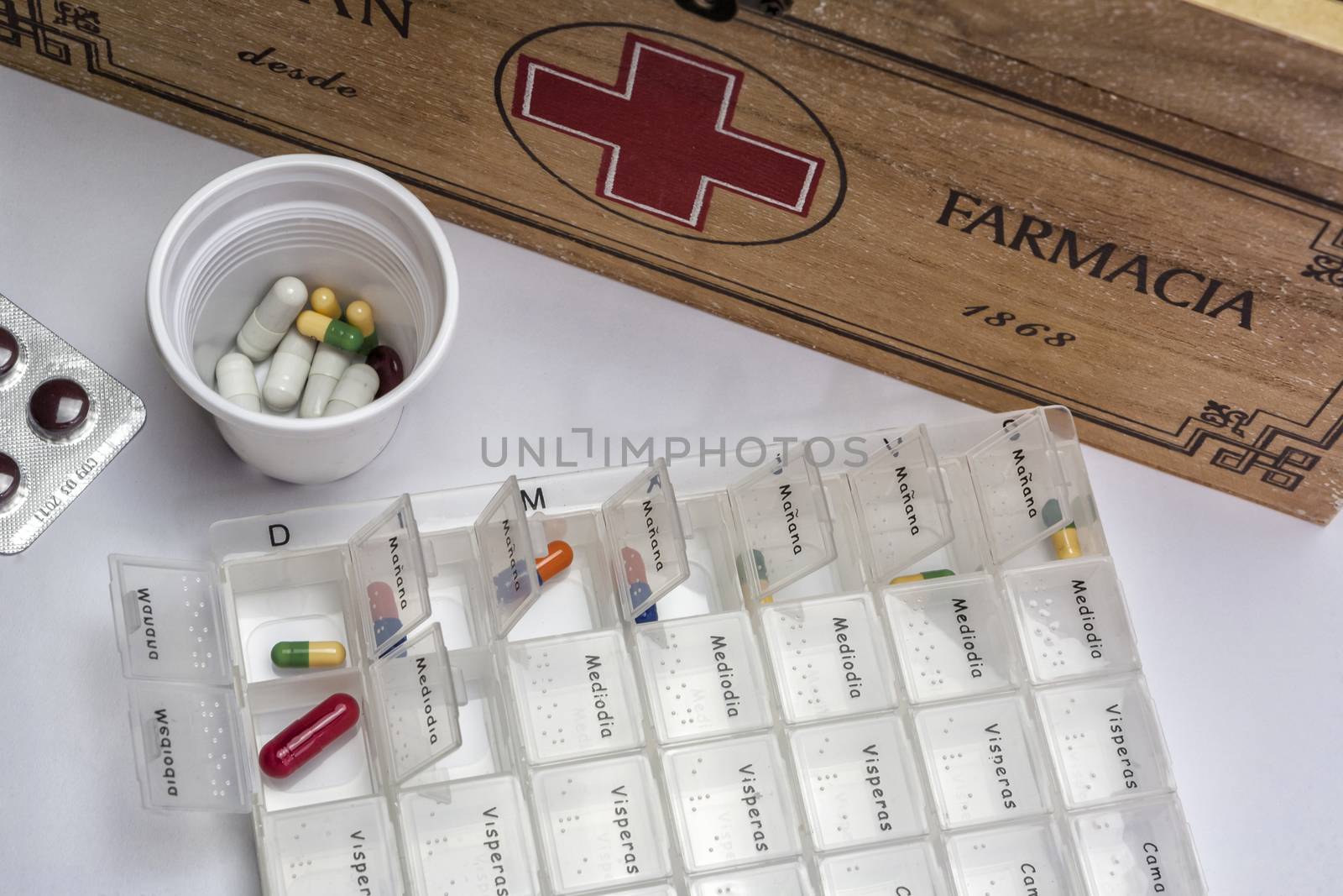 Pills with pill organizer next to old wood kit by digicomphoto