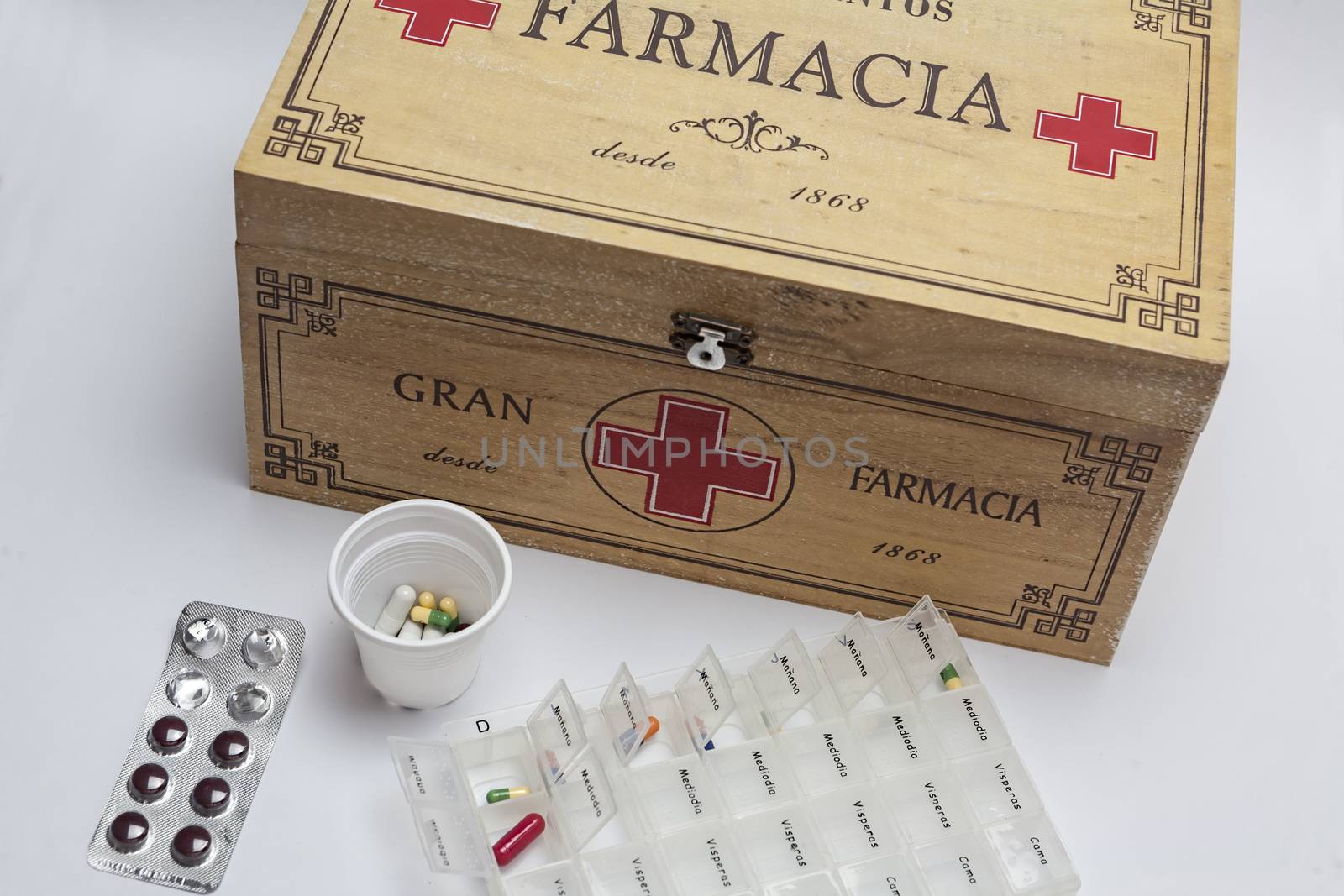 Pills with pill organizer next to old wood kit