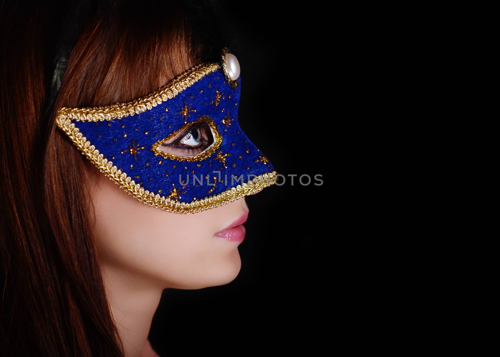 Beautiful caucasian brunette in carnival mask over black background