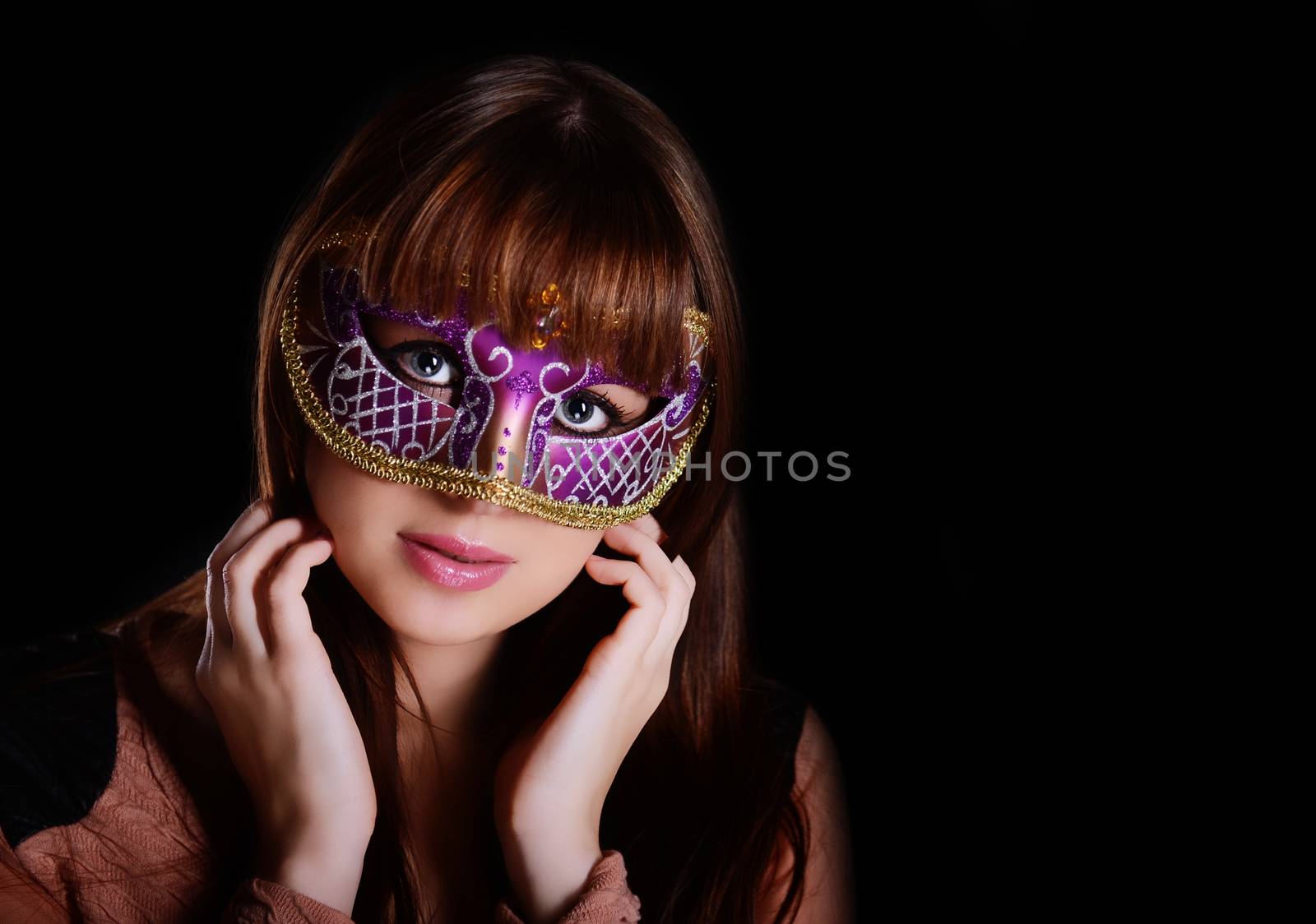 Beautiful caucasian brunette in carnival mask over black background