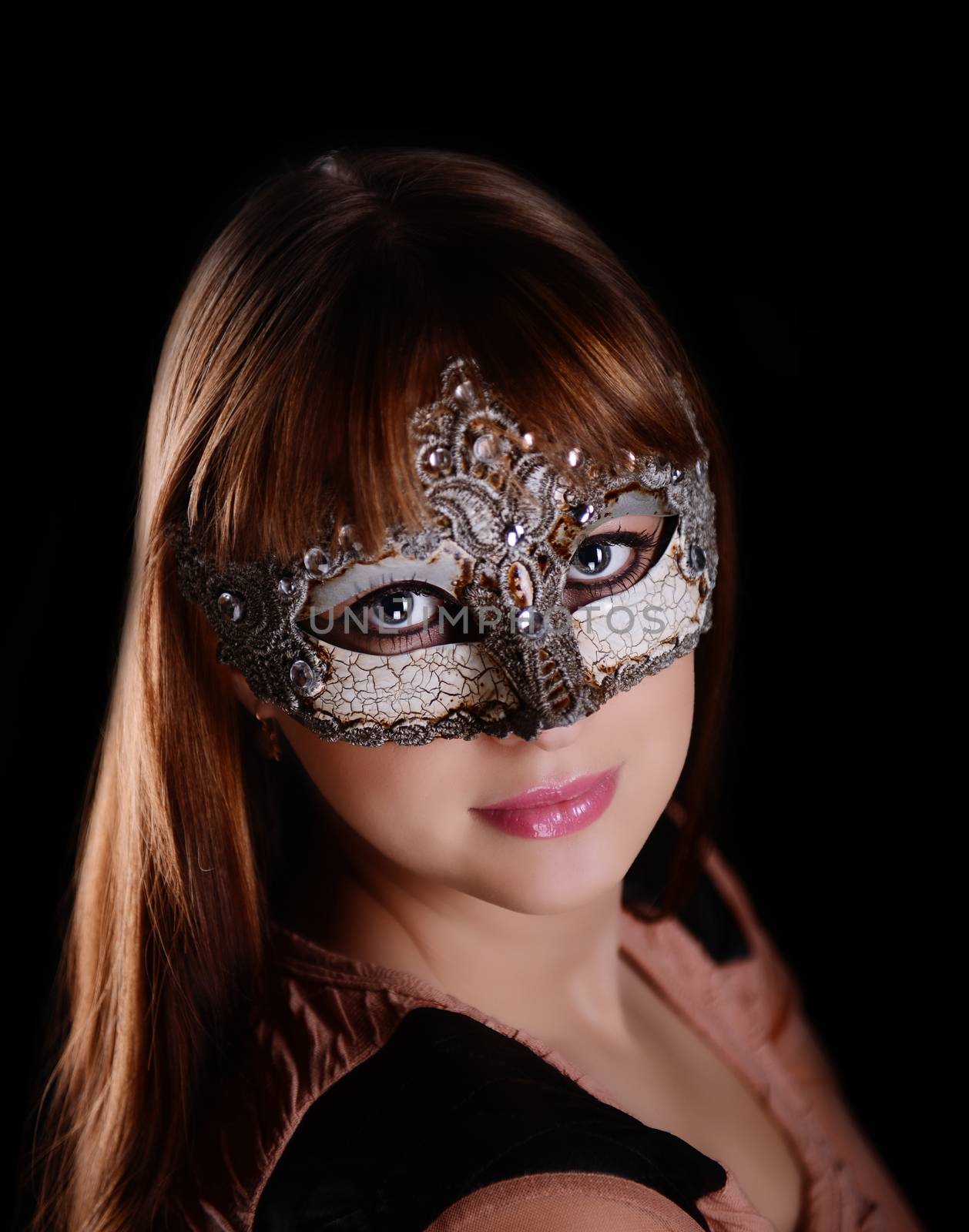 Beautiful caucasian brunette in carnival mask over black background