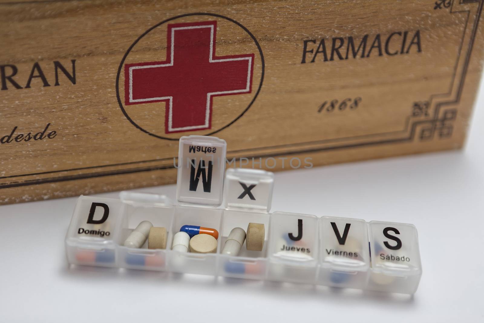 Pills with pill organizer next to old wood kit